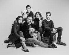 a group of people sitting next to each other in front of a white background with a dog