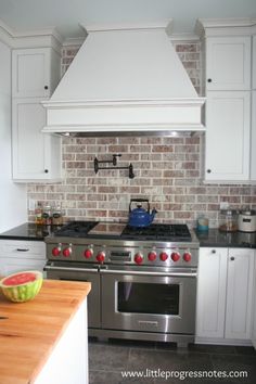 a stove top oven sitting inside of a kitchen next to a wooden cutting board with fruit on it