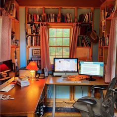 a computer desk with two monitors and a laptop on it in front of a bookshelf