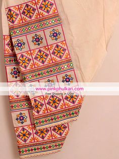 an orange and pink patterned cloth hanging on a wall next to a white shirt with colorful geometric designs