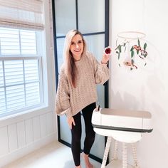 a woman standing next to a white table holding a piece of paper with flowers on it