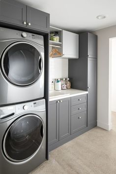 a washer and dryer in a small room with gray cabinets on the wall