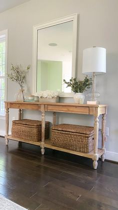 a wooden table topped with baskets under a mirror