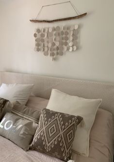 a bed topped with lots of pillows next to a wall mounted art piece on the wall