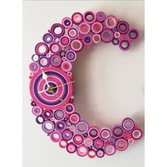 a pink and purple clock with circles on it's face sitting on a white surface