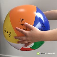 a child's hand reaching for an inflatable ball with numbers on it