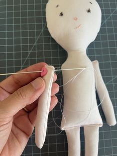 someone is stitching the thread on a doll's head to make it look like they are holding something