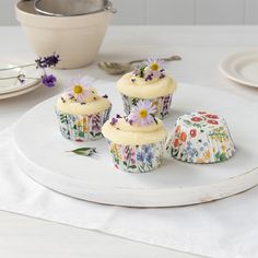 three cupcakes on a white plate with flowers