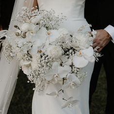 the bride and groom are holding bouquets of white flowers in their hands while walking together