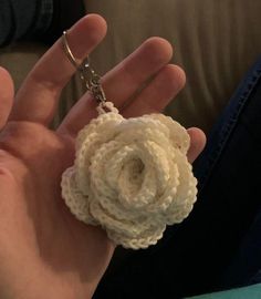 a hand holding a crocheted flower with a ring on it's thumb