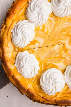 a cheesecake with whipped cream on top is sitting on a table next to a knife