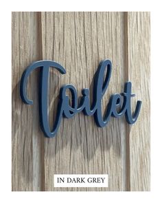 the word toilet in dark grey on a wooden surface