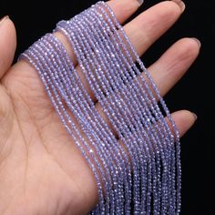 a woman's hand holding several strands of purple beads