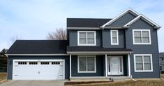 a large blue house with two garages on the front and one car door open