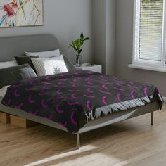 the bed is made up with purple and black comforter on it's side