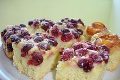 several pieces of cake on a plate with fruit toppings and powdered sugar over them