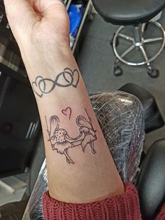 a person with a tattoo on their arm holding onto the wrist and another hand that has a heart in it