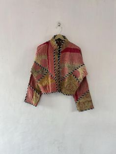 a jacket hanging up on a wall next to a white wall with a red and gold pattern