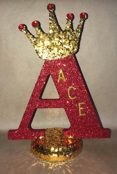 a red and gold glitter letter with a crown on top