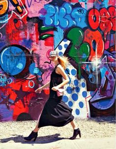 a woman walking in front of a colorful wall