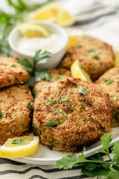 several crab cakes on a plate with lemon wedges and parsley garnish