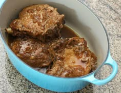 a blue pot filled with meat covered in gravy on top of a counter