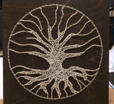 a wooden plaque with a wire work tree on it's face and roots in the shape of a circle