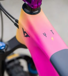 the front end of a bike with pink and yellow paint on it's handlebars