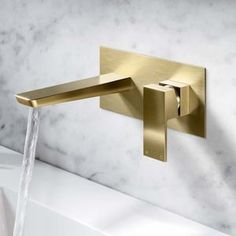 a gold faucet with water running from it's spout in a bathroom