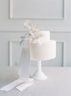 a white wedding cake with ribbon on top