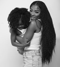 two young women hugging each other with long hair on their shoulders and one holding the back of her head