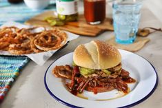 a pulled pork sandwich on a plate with onion rings