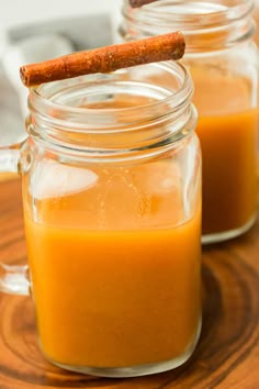 two glass jars filled with orange liquid and cinnamon stick