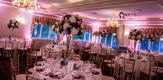 the tables are set up for a wedding reception with floral centerpieces and chandeliers