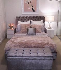 a bedroom with a bed, ottoman and pictures on the wall above it's headboard