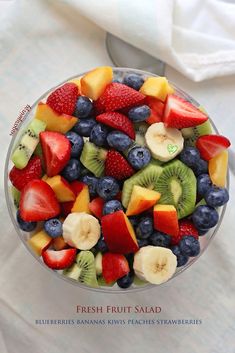 fresh fruit salad with blueberries, bananas, kiwis and strawberries in a glass bowl