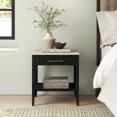 a nightstand with a potted plant sitting on top of it next to a bed