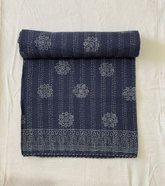 a blue and white cloth folded on top of a bed with an intricate design in the middle