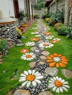 a garden with rocks and flowers painted on the grass in front of a house,