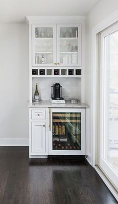 a kitchen with white cabinets and wood floors