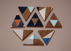 several pieces of wood are arranged in the shape of triangulars on a pink wall