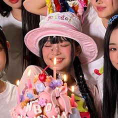 a group of young women standing next to each other in front of a birthday cake