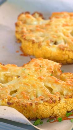 two cheesy pizzas sitting on top of a baking sheet covered in cheese