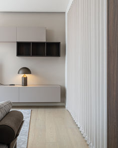 a modern living room with white walls and wood flooring on the side, along with an upholstered sofa