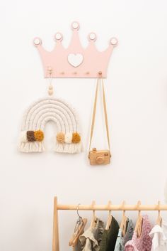 a white wall with some clothes and a pink crown hanging on it's side