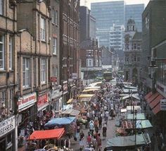 a busy city street filled with lots of people walking around and shops on both sides