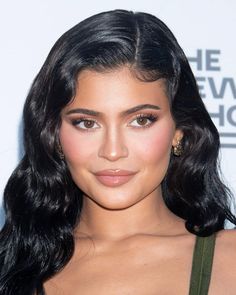 an image of a woman with long black hair and brown eyeshade wearing gold earrings