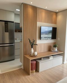 a television mounted on the wall in a living room next to a refrigerator and freezer