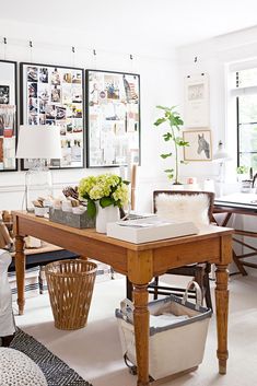 a living room with pictures on the wall and a desk in front of a window