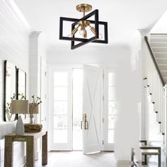 an entry way with white walls and wood flooring, two chandeliers hanging from the ceiling